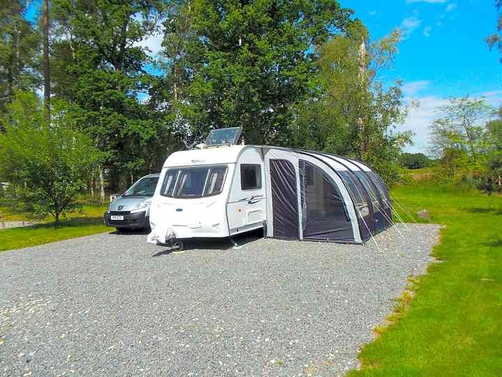 A touring caravan on a spacious hardstanding pitch at Woodhall Country Park