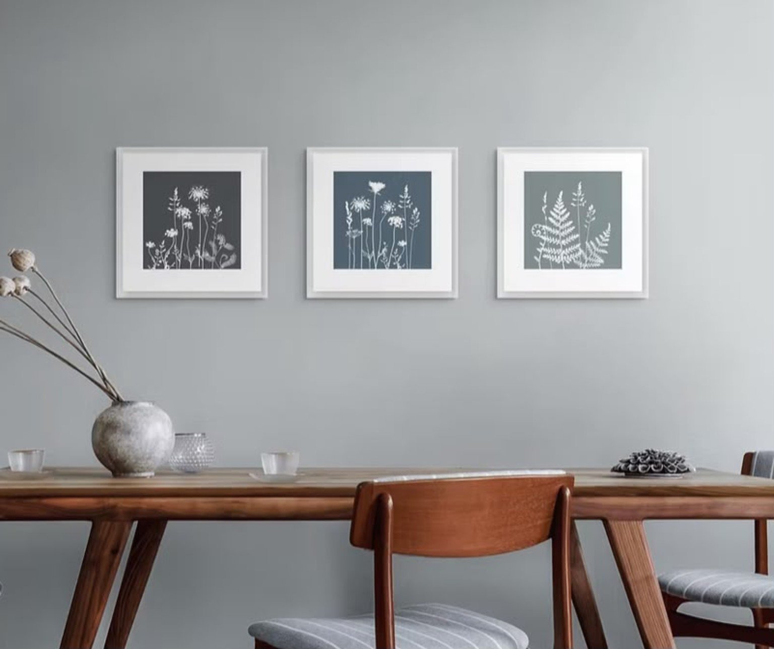 Three framed botanical prints displayed above a wooden dining table