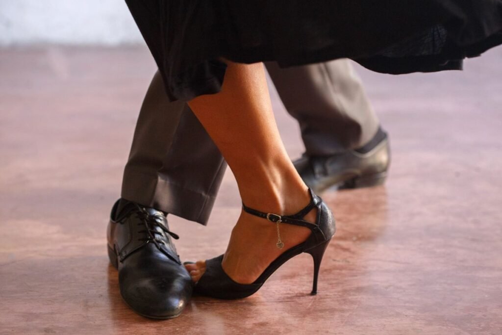 Close-up of a dancing couple’s shoes on a wooden floor; representative dance photograph