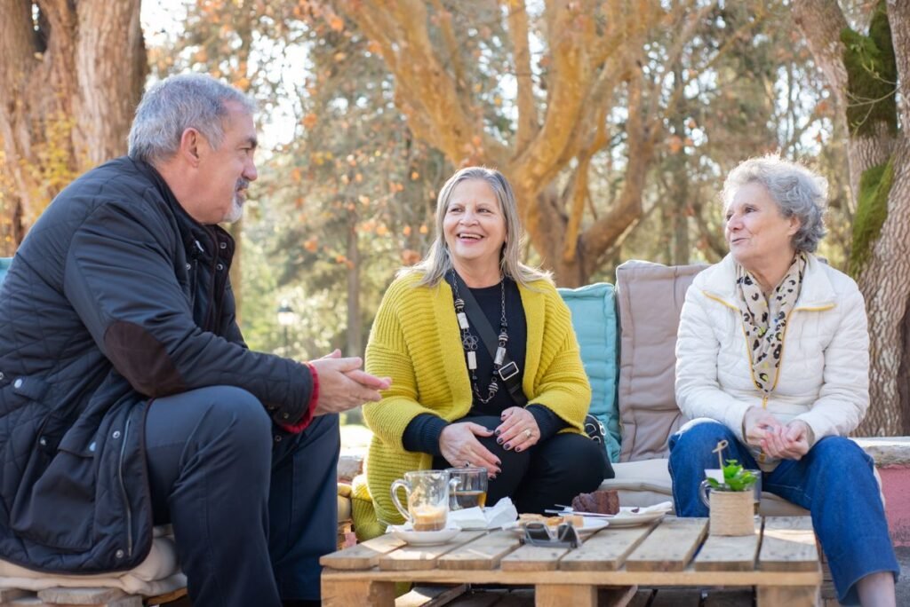 Three adults talking over tea outdoors; representative friendship photograph