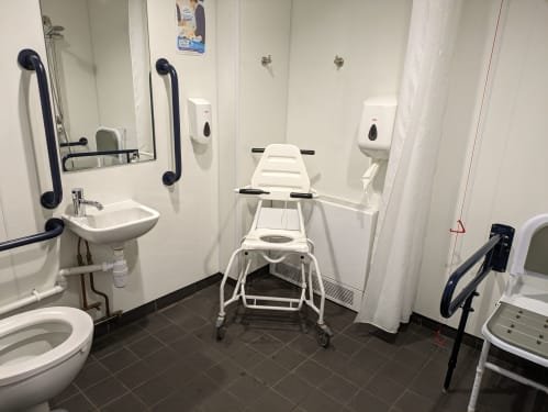 Accessible shower room with support rails and a wheeled shower chair at Jubilee Park, Woodhall Spa