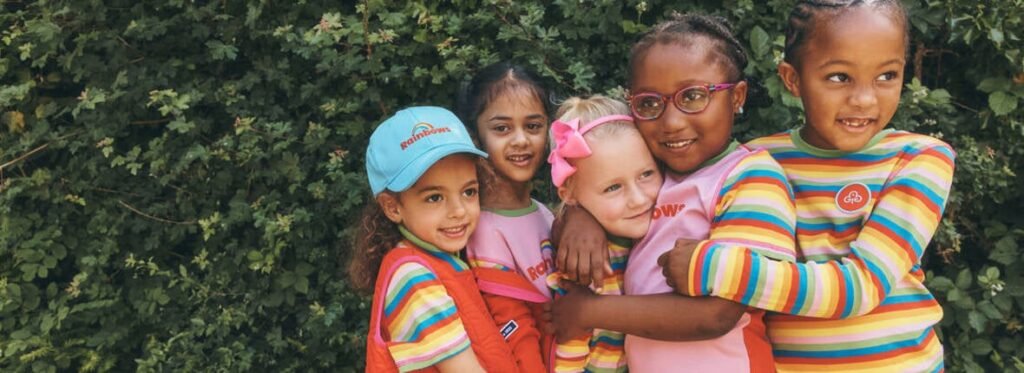 Rainbows in colourful uniforms smiling together outdoors; representative Girlguiding photograph