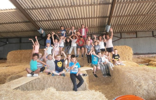 Children sitting on hay bales during a visit to Rand Farm Park