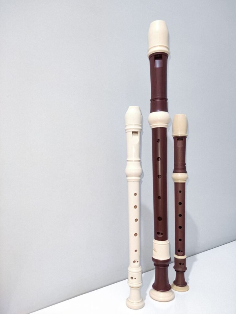 Three recorders of different sizes standing against a pale wall; representative music photograph
