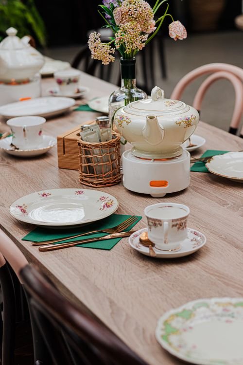 Floral teapot, cups and plates arranged on a table; representative social meeting photograph