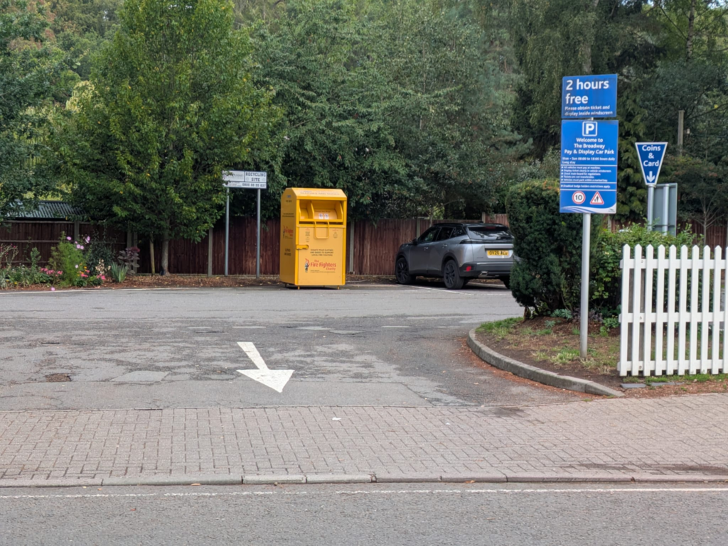 Entrance to The Broadway car park in Woodhall Spa, with parking signs and a white fence